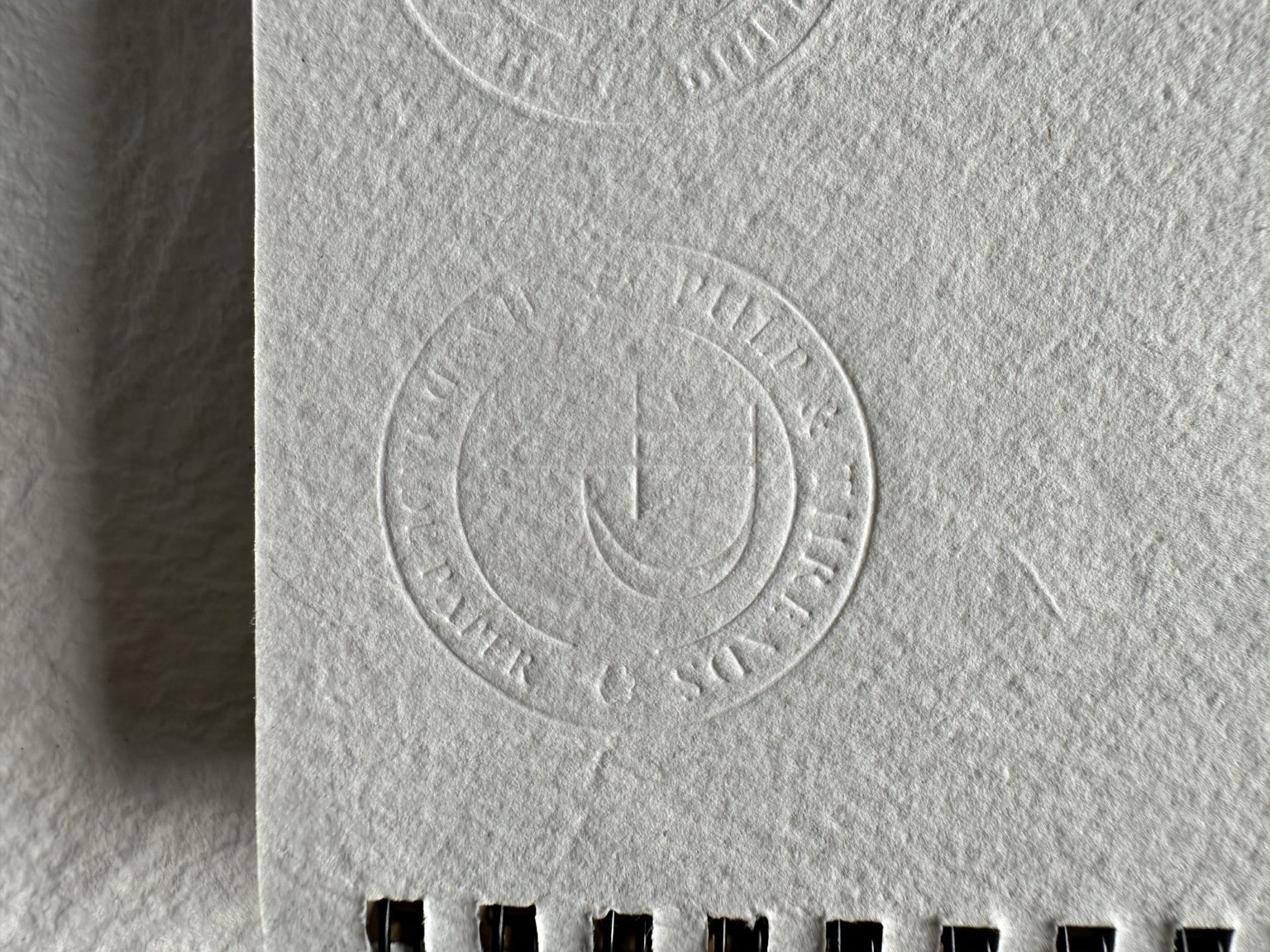A blind-embossed Pulp & Threads seal on a textured handmade paper cover
